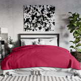 Liberator Fascinator King throw in Merlot covering a bed in a room with framed artwork and plants